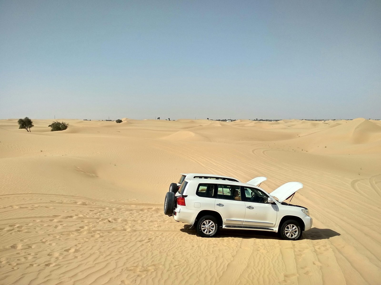 A 4x4 stuck in desert sand with people working to free it