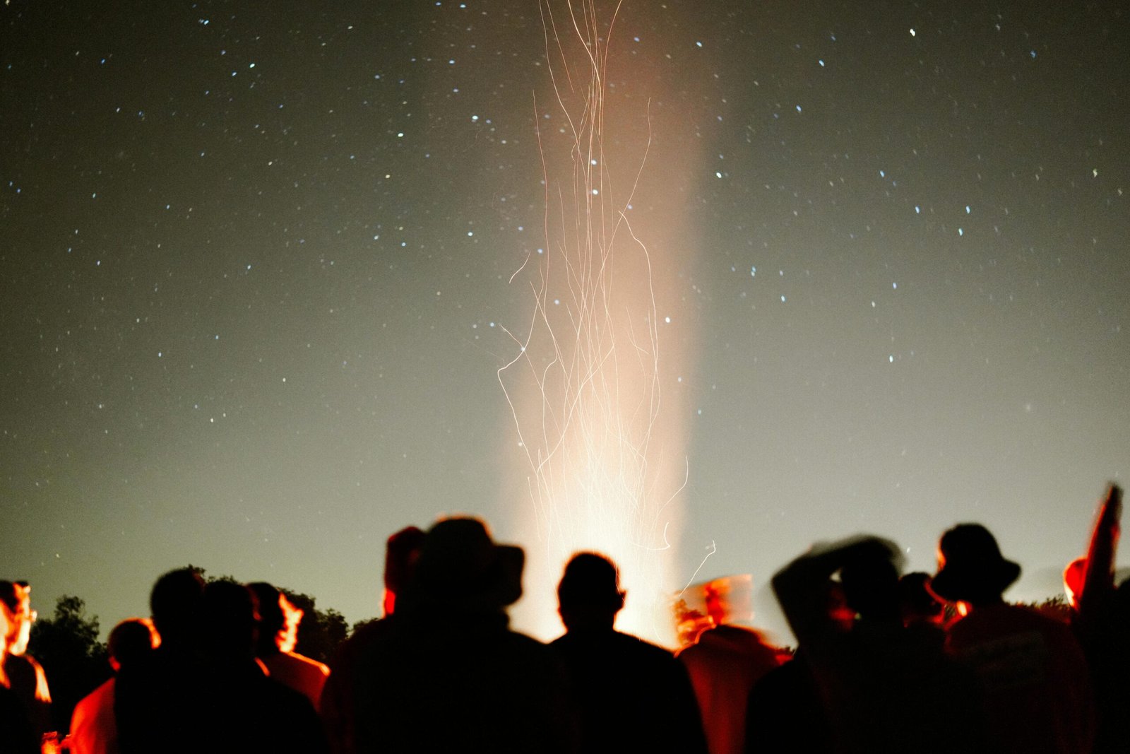 A group gathered around a crackling fire under a blanket of stars