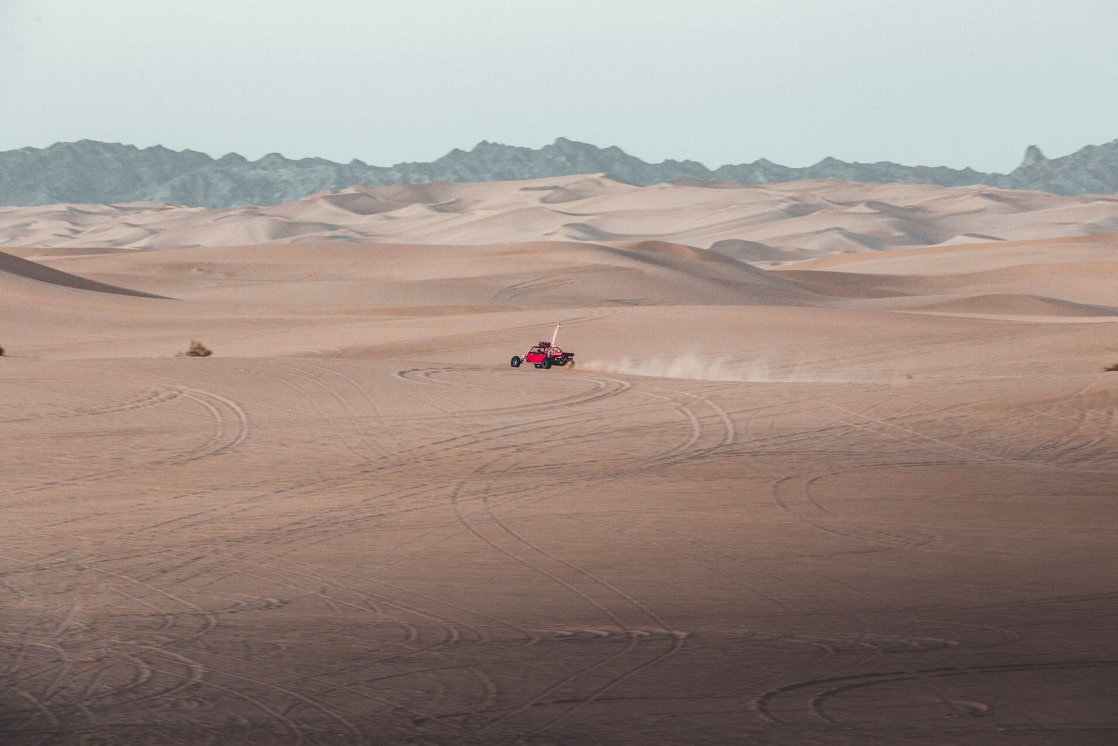A person riding a quad bike across a sandy desert landscape.