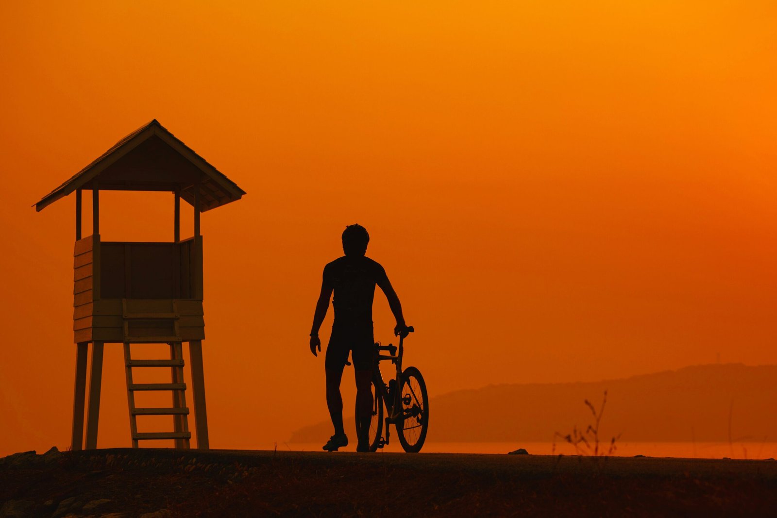 A quad bike silhouetted against a bright orange sunset over the desert.