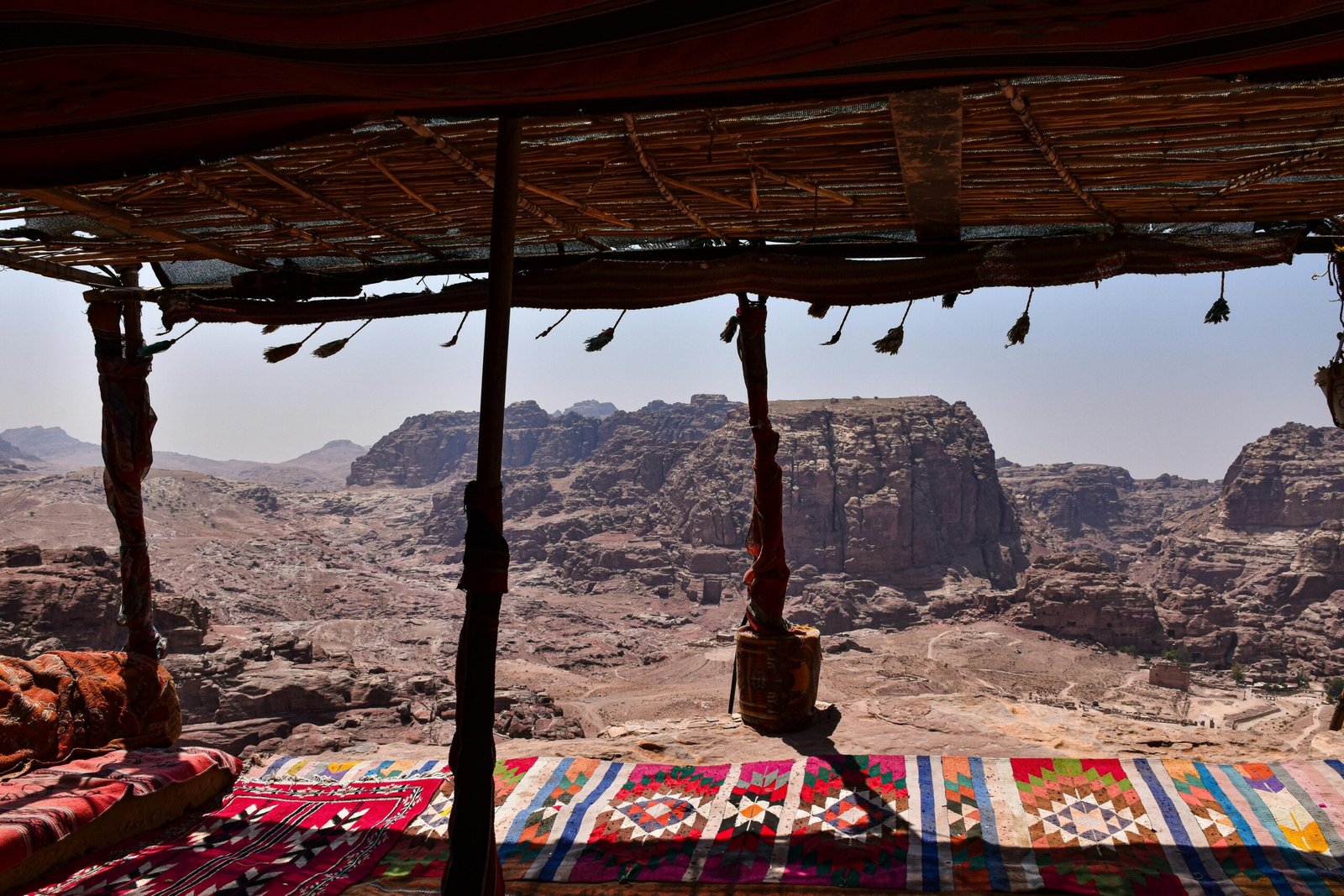 A spread of Middle Eastern dishes served on colorful rugs near a desert camp