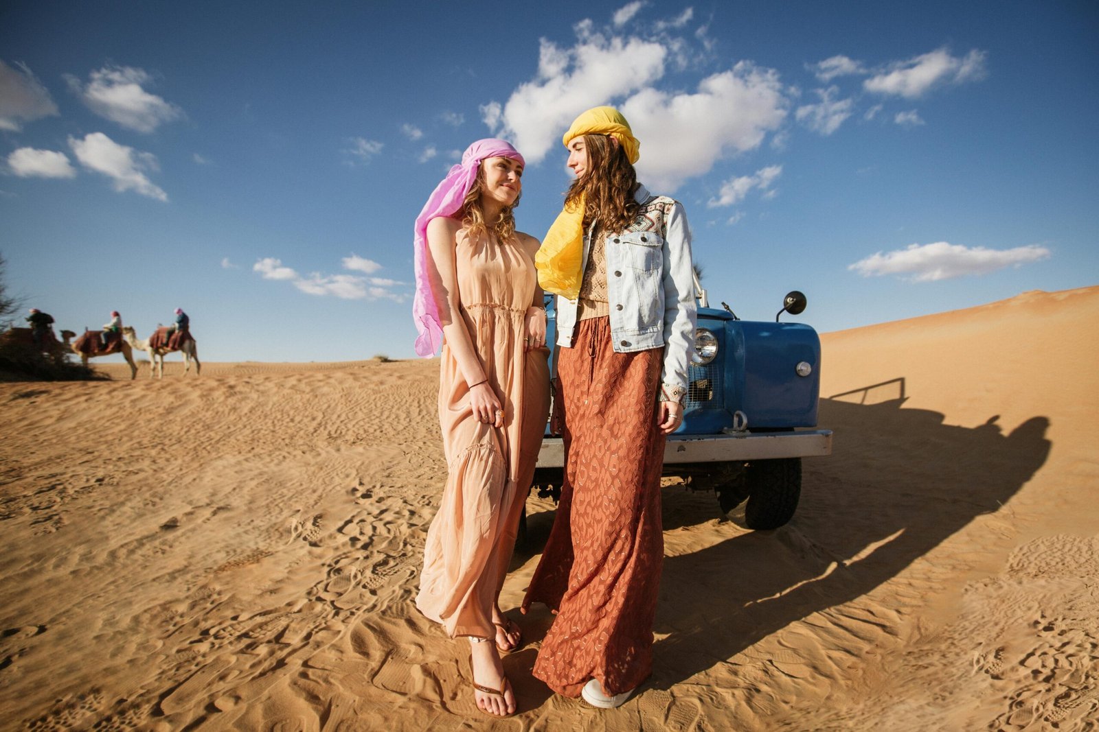A traveler holding sand dune navigation tools while standing beside a jeep in the Sahara Desert