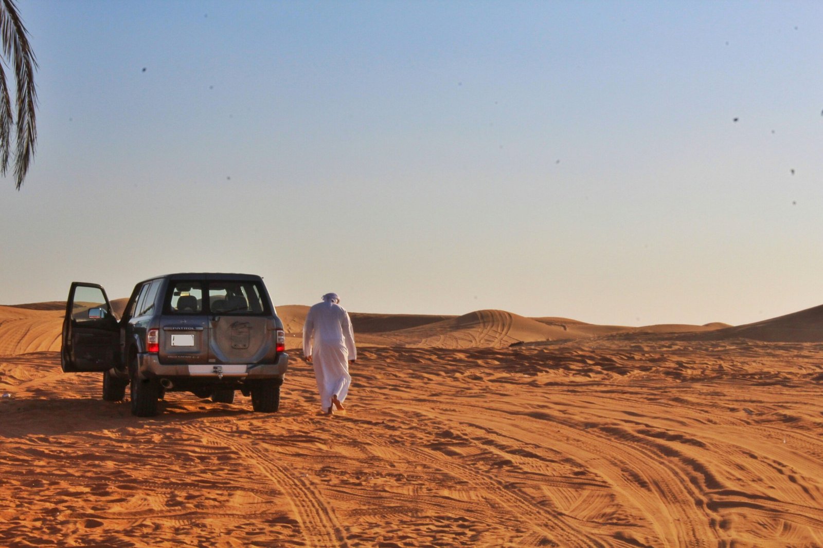 A traveler using a phone app to navigate across a sandy path during a desert safari
