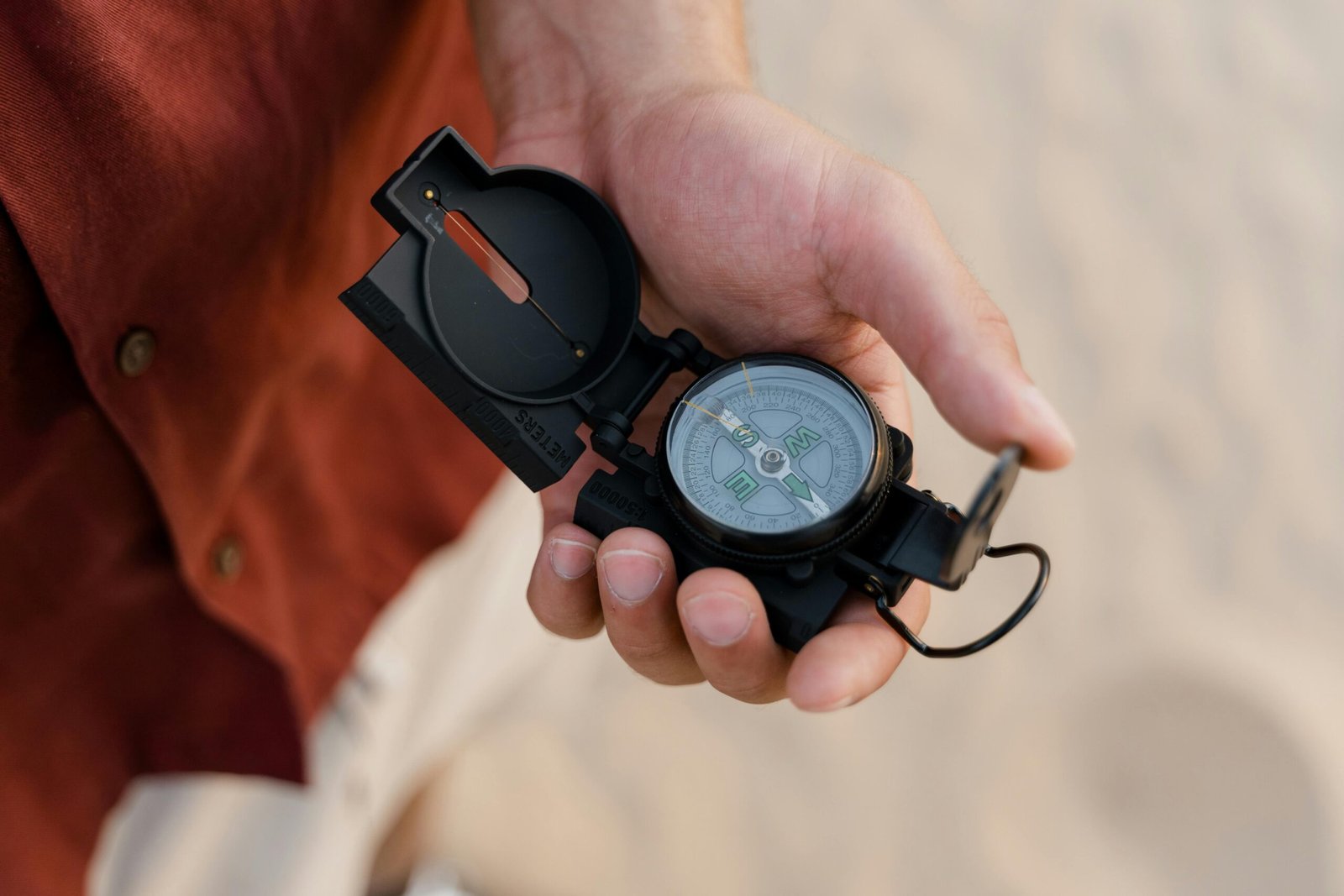 Adventurer celebrating atop a large sand dune after successfully completing his journey with navigation tools visible