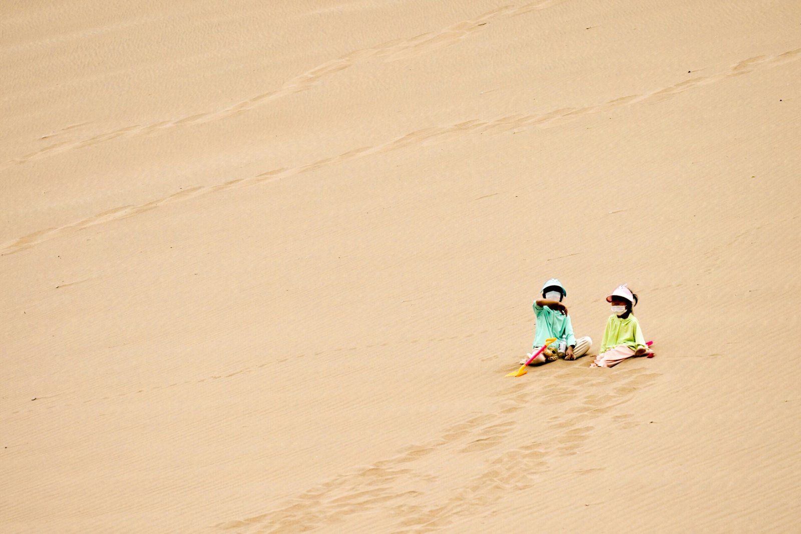 Tourists sitting on sand dunes pointing at constellations.