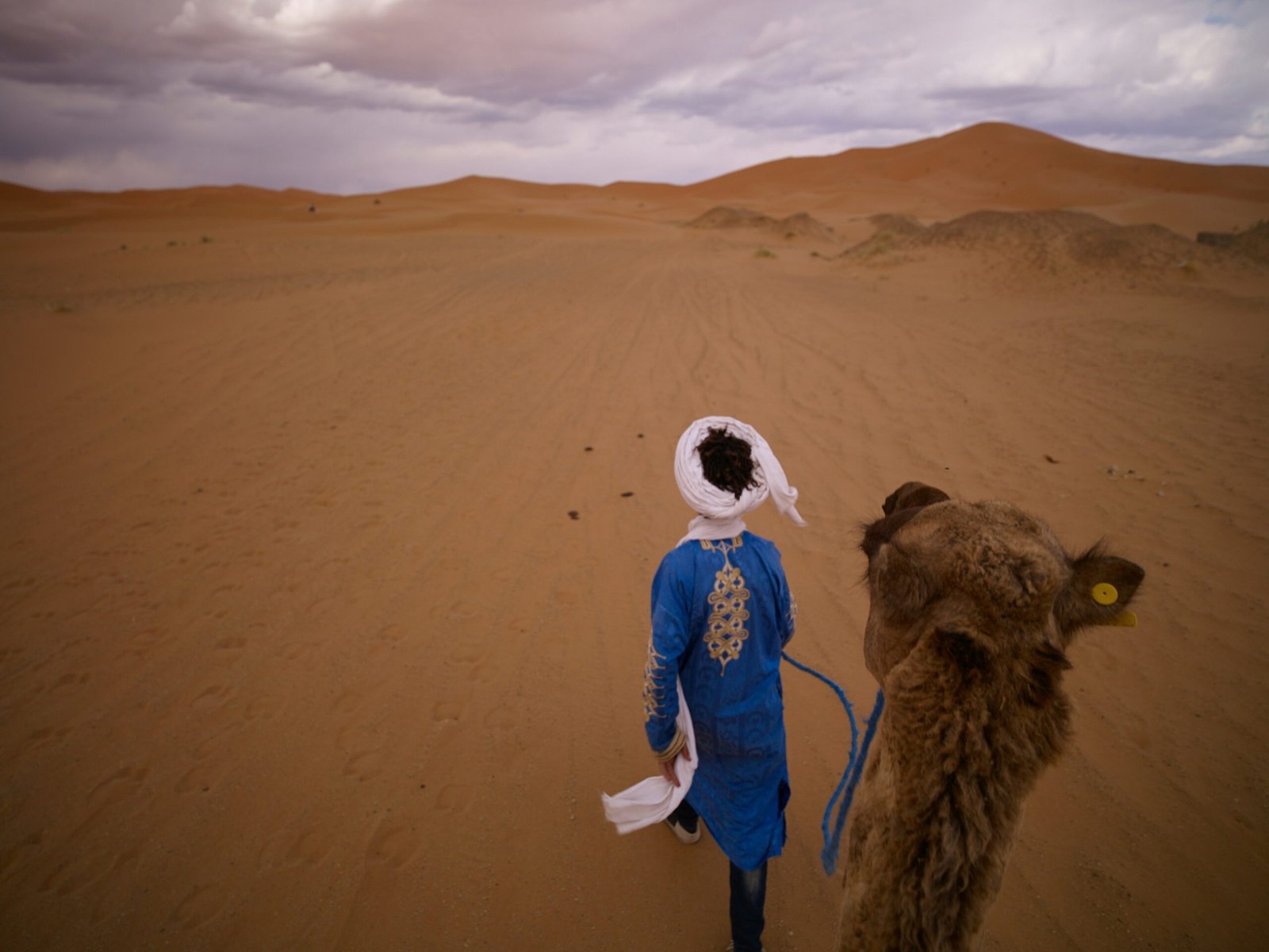 A smiling local guide holding a map near towering sand dunes