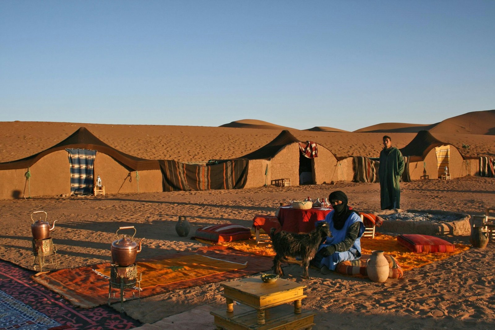 A traditional goat-hair tent at Berber Camp Sahara with colorful rugs inside.