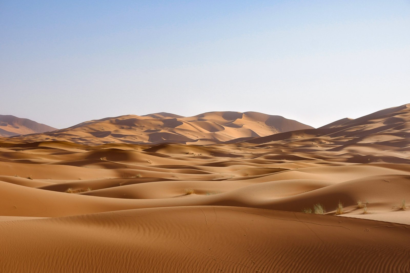 A young woman sliding down a steep sand dune on a sandboard