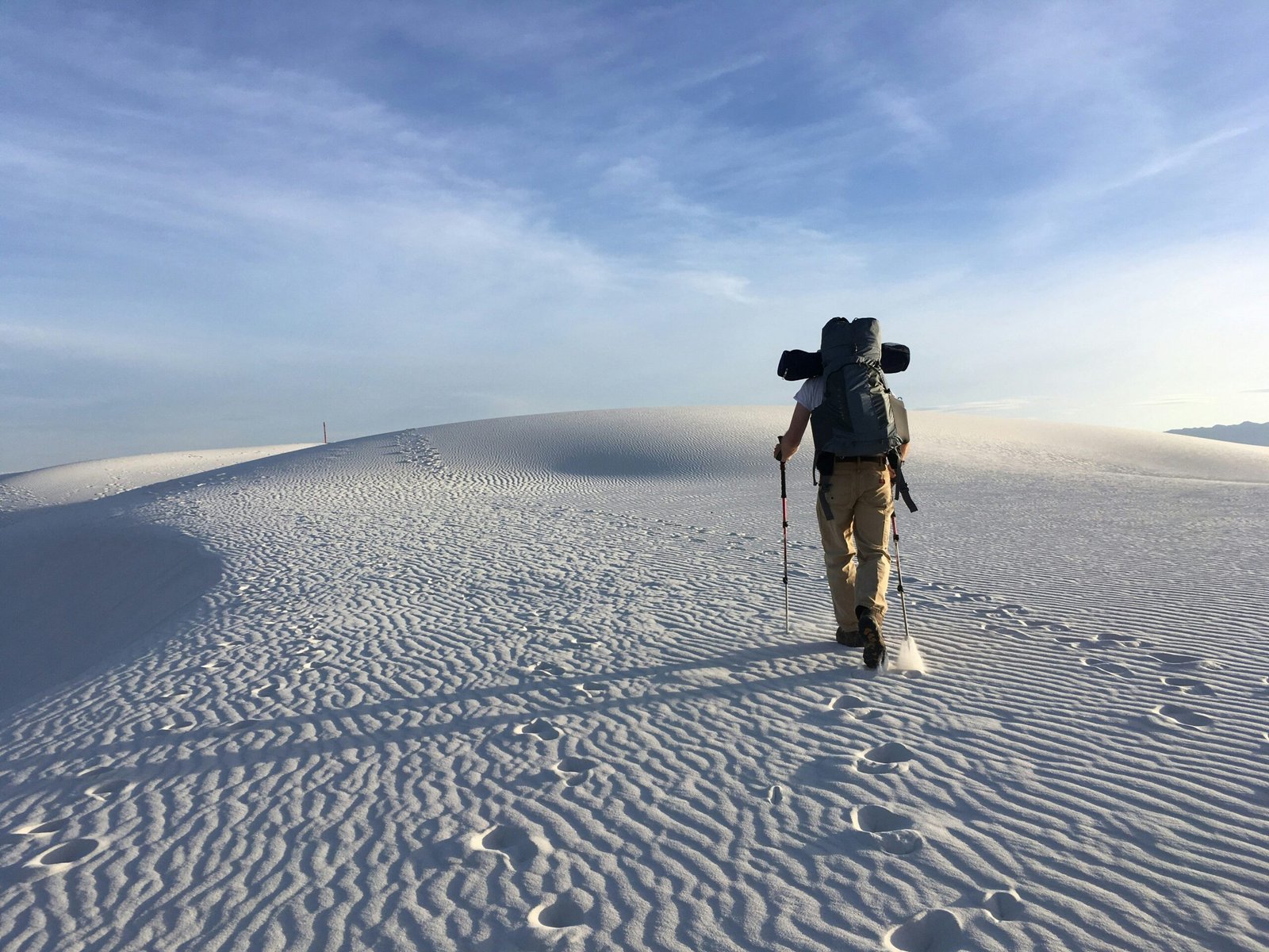 An SUV navigating challenging sand dunes, kicking up clouds of dust.