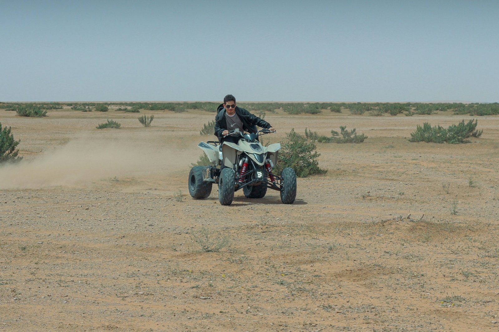 Smiling woman confidently riding a quad bike across desert terrain