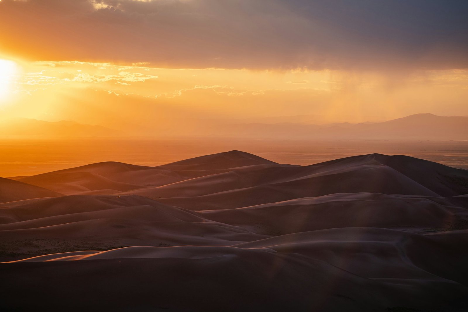 A sunrise glowing over vast golden sand dunes during a desert safari