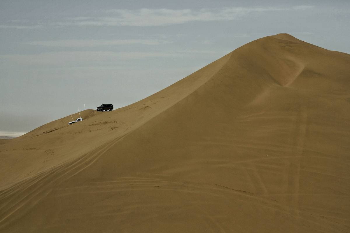 An adventurer driving a dune buggy on steep sandy slopes