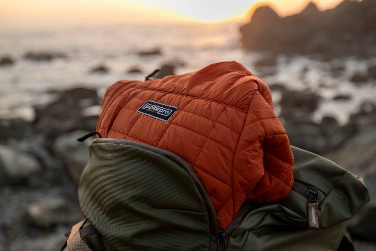Tourists riding camels near sand dunes at sunset