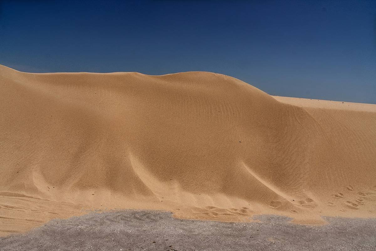 Traveler midway down a massive sand dune on a sandboard