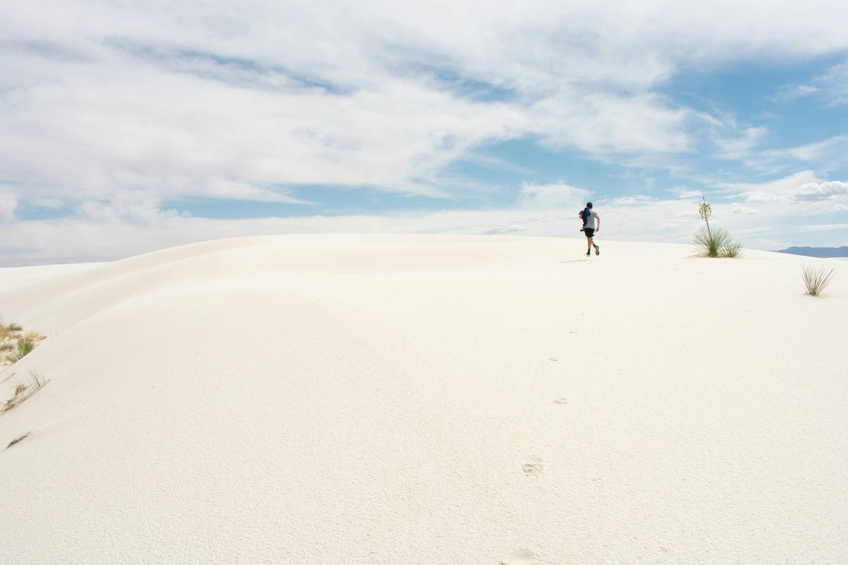 A group of tourists riding camels across rolling desert dunes