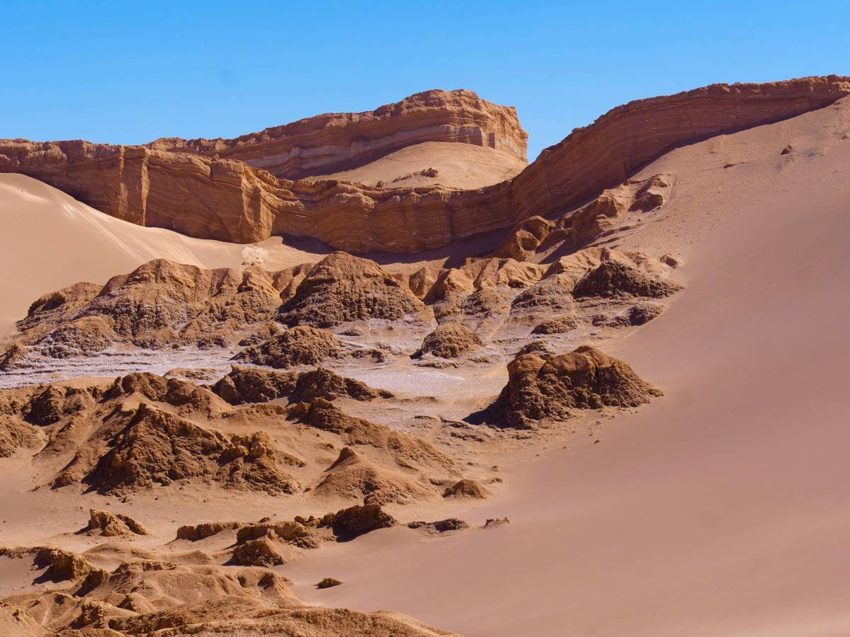 A jeep climbing a steep sandy dune during a desert safari at sunset
