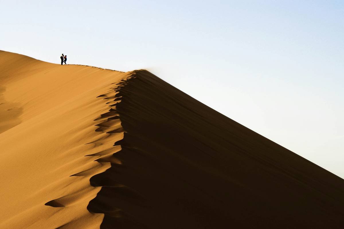 Family standing on golden sand dunes during sunset