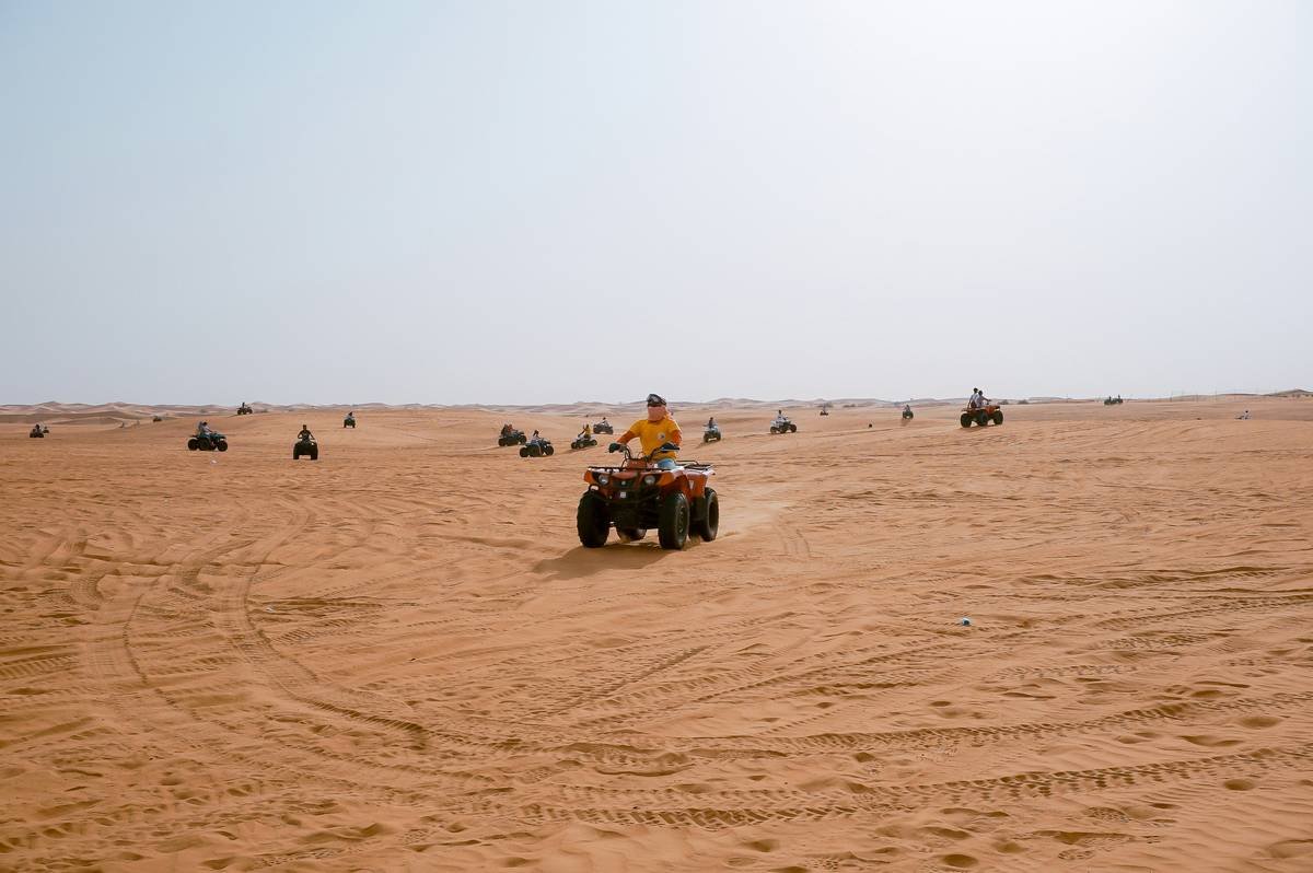 Group riding camels across golden desert landscape