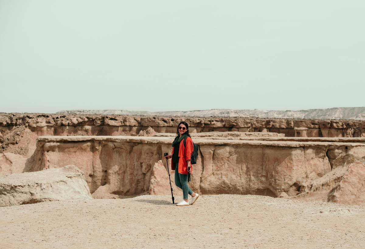 Infographic showing ideal desert hiking outfit layers with UV protection ratings, fabric types, and temperature ranges