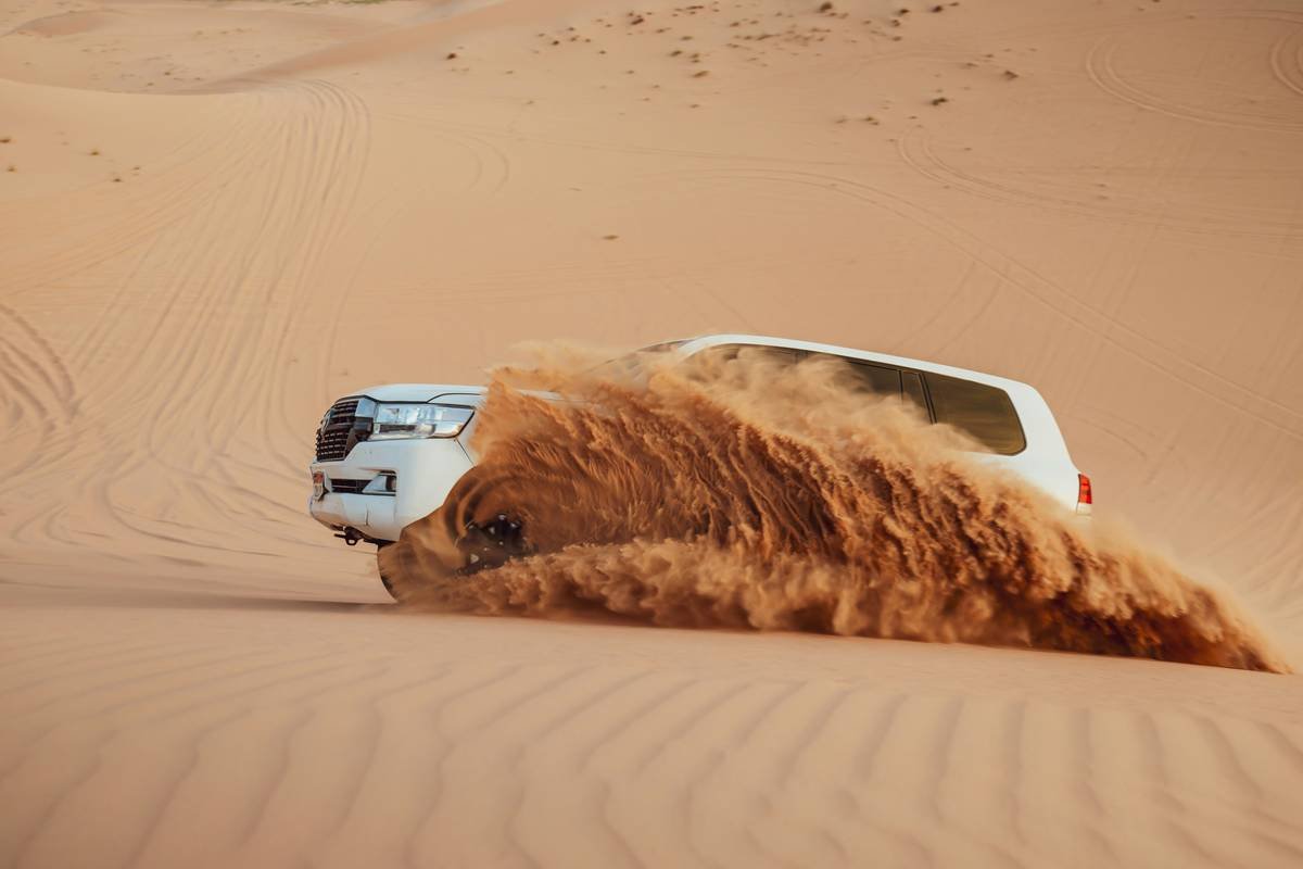 intense dune bashing in the desert showing vehicle airborne over a crest with desert horizon backdrop