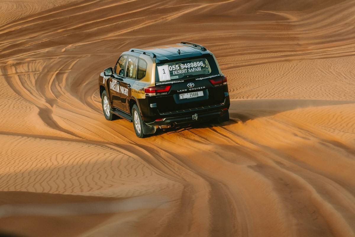 dune bashing in the desert with a modified 4x4 climbing a golden sand dune at sunset